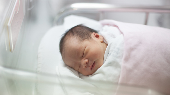 new born infant asleep in the blanket in delivery room