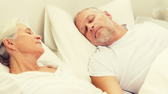 happy senior coupler lying in bad at home