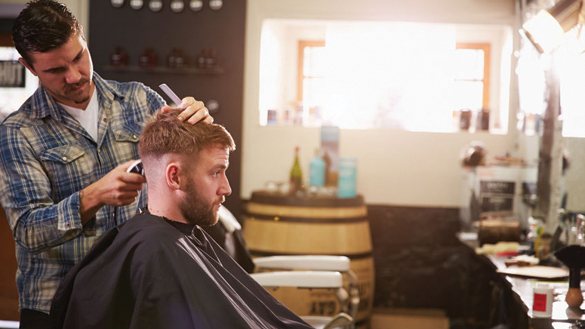 41393140 - male barber giving client haircut in shop