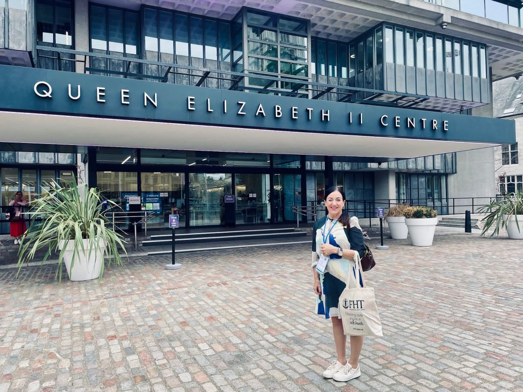 Maria Mason smiling outside of the Queen Elizabeth 2 Centre ready for the Integrated and Personalised Medicine Congress